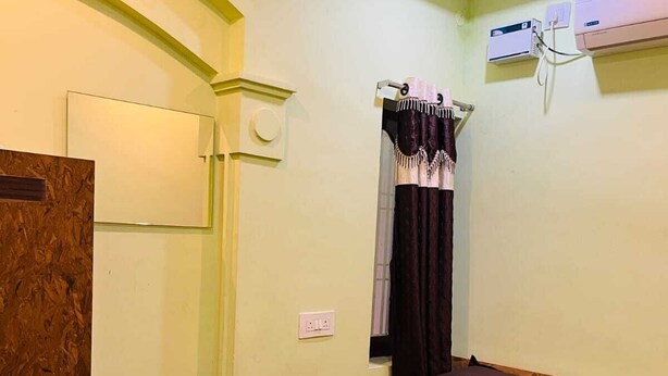 Een kamer met een bed, een plafondventilator, een airconditioning en een houten hoofdeinde.