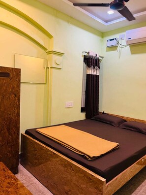 A room with a bed, a ceiling fan, an air conditioning unit, and a wooden headboard. - Thashmika Residency (Tiruvannamalai)