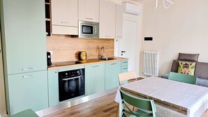 Et moderne køkken med mikrobølgeovn, ovn og vask. Spisebord med stole og en radiator.