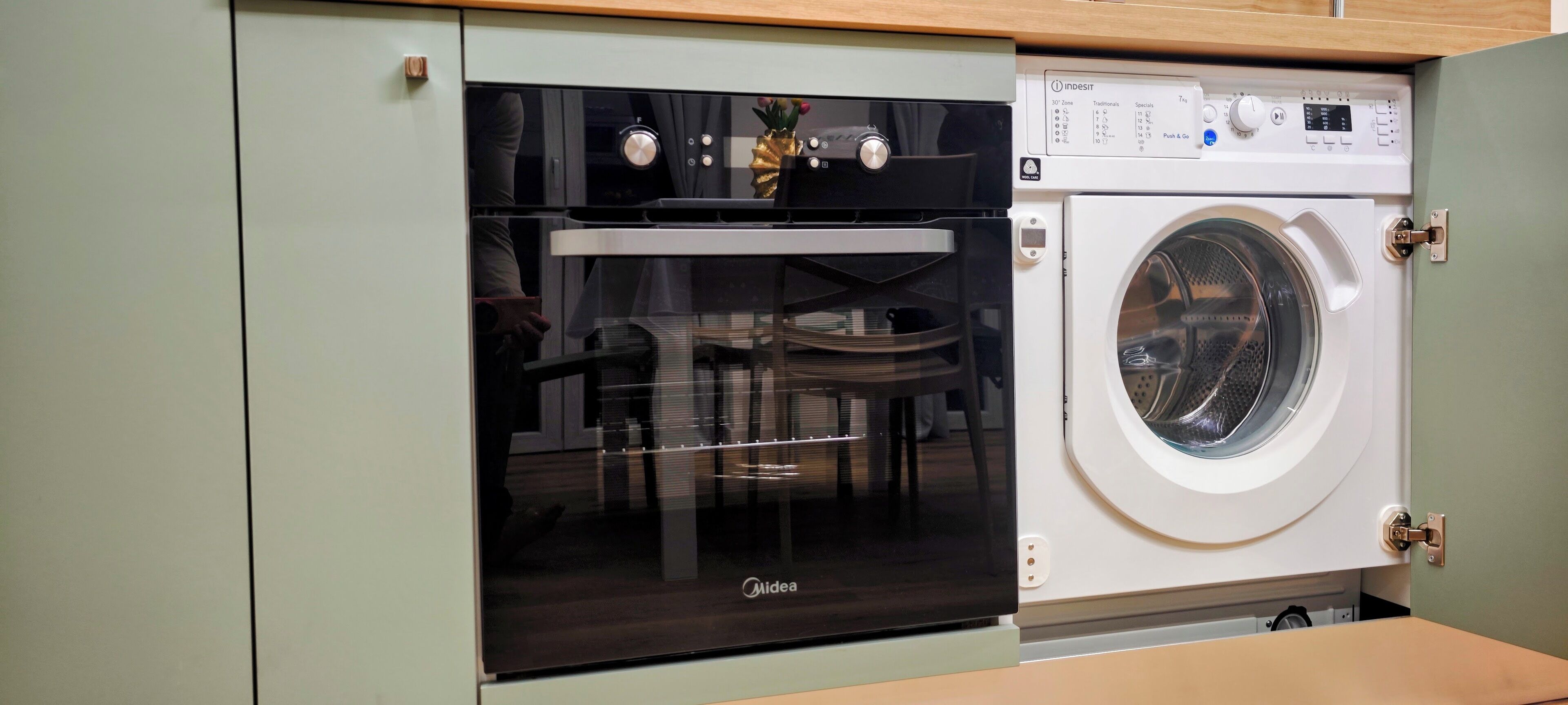 A compact kitchen with a built-in oven and a washing machine.