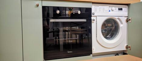 A compact kitchen with a built-in oven and a washing machine.