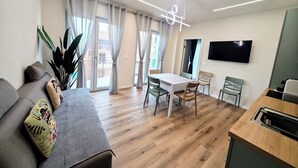 En moderne stue med sofa, spisebord, stole og fjernsyn.