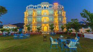 A large, ornate building with multiple balconies and a well-lit entrance. - Aryavarta A boutique abode (Udaipur)