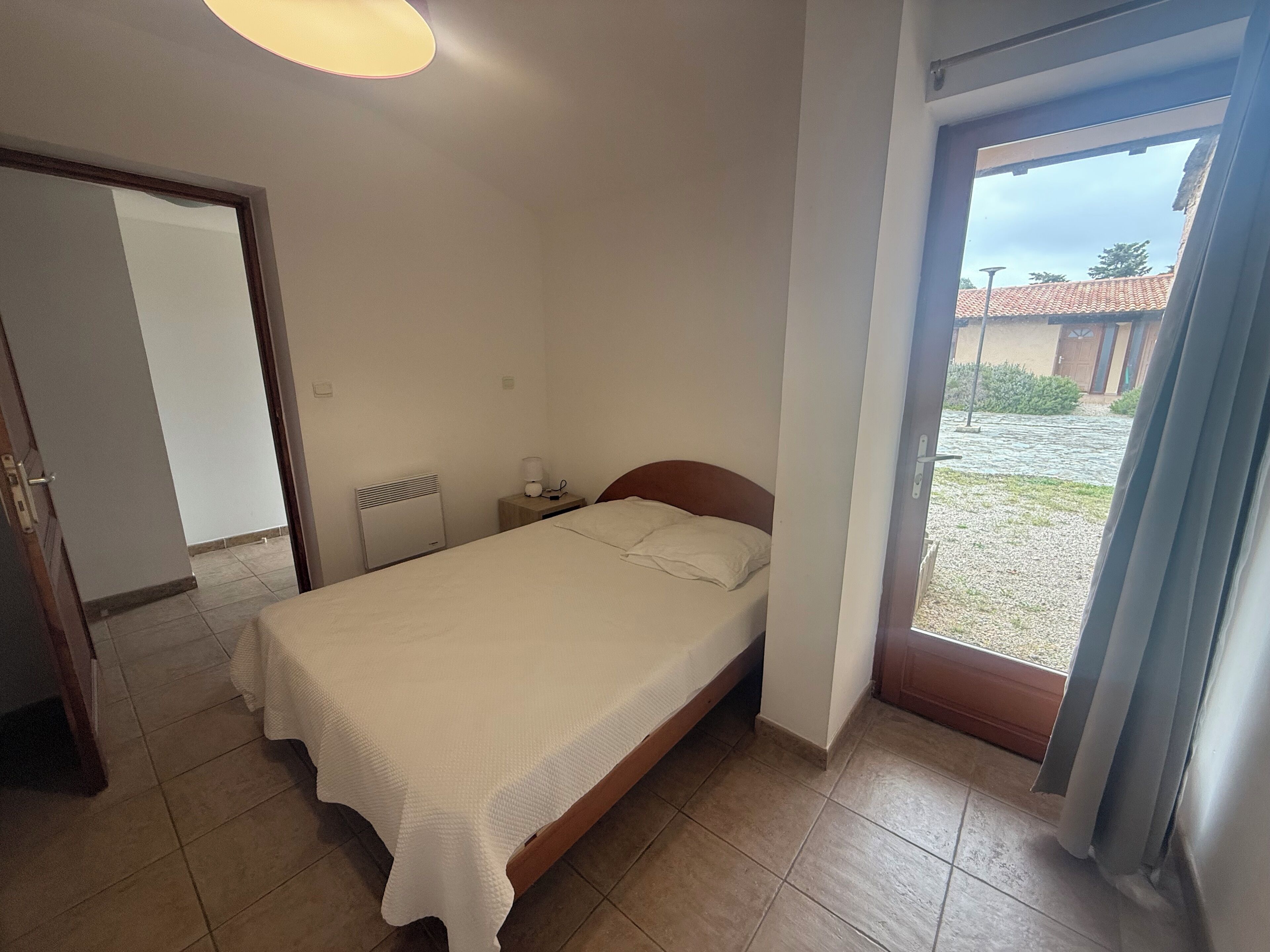 Een eenpersoonsbed in een kamer met uitzicht op een binnenplaats.