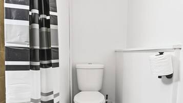 A bathroom with a toilet, a paper towel dispenser, and a striped shower curtain.