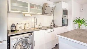 Une cuisine compacte équipée d’un lave-linge, d’un four à micro-ondes et d’un évier.