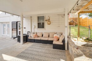 Une véranda avec un canapé d’angle beige, une tête de cerf accrochée au mur et un tapis à motifs.