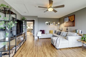 A modern living room with a sectional sofa, a ceiling fan, and a bookshelf filled with plants. - Near Hiking Trails! Luxe Family Home in Lakeside (Lakeside)