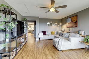 A modern living room with a sectional sofa, a ceiling fan, and a bookshelf filled with plants. - Near Hiking Trails! Luxe Family Home in Lakeside (Lakeside)