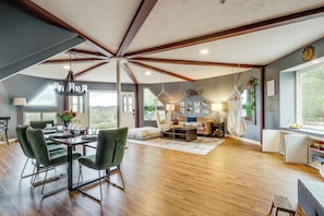 A spacious living area with a dining table, green upholstered chairs, a sofa, and a hanging chair. - Near Hiking Trails! Luxe Family Home in Lakeside (Lakeside)