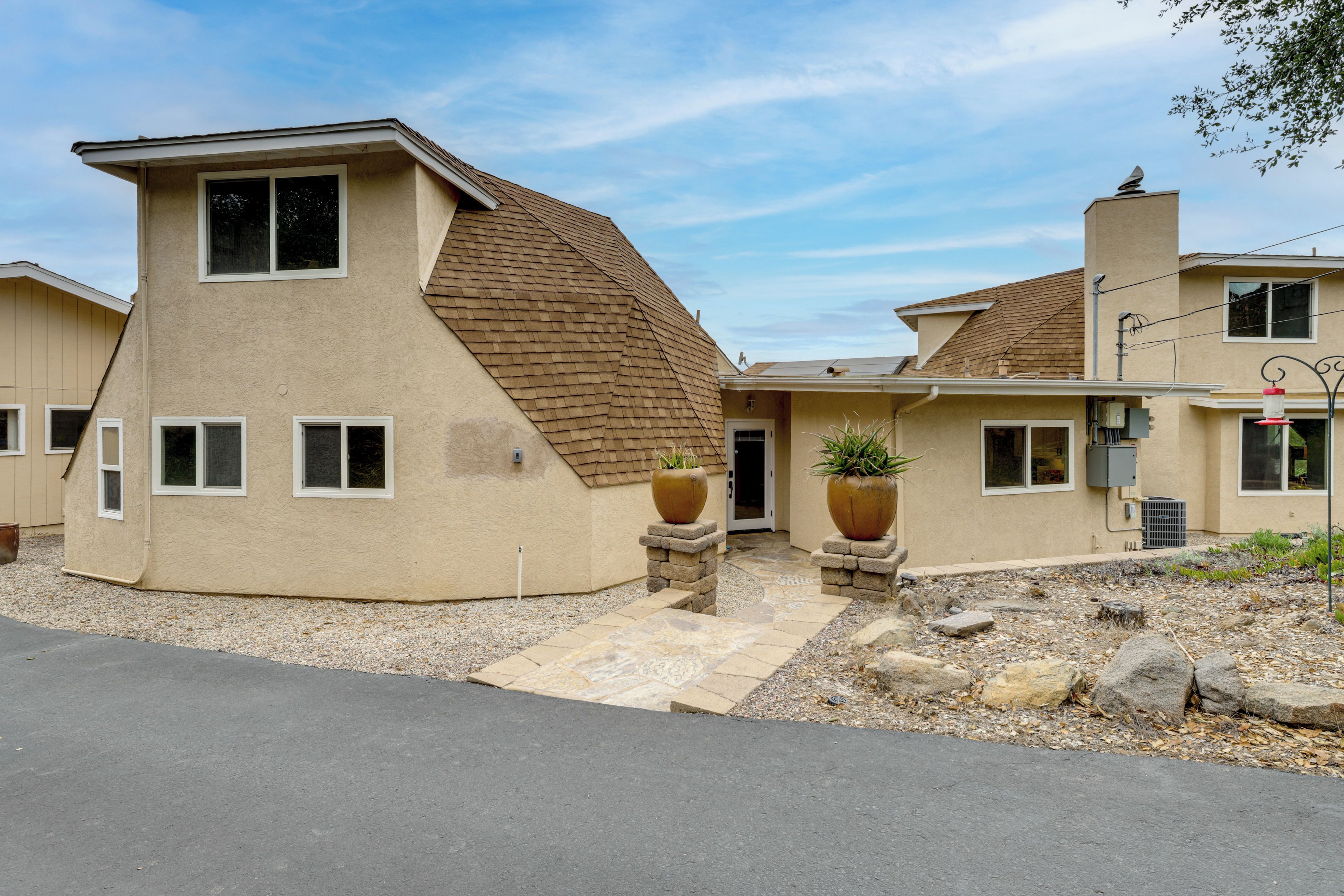A two-story house with a sloped roof, a front entrance, and two large planters.