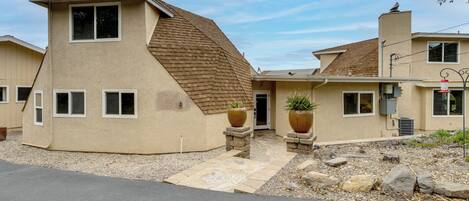 A two-story house with a sloped roof, a front entrance, and two large planters.