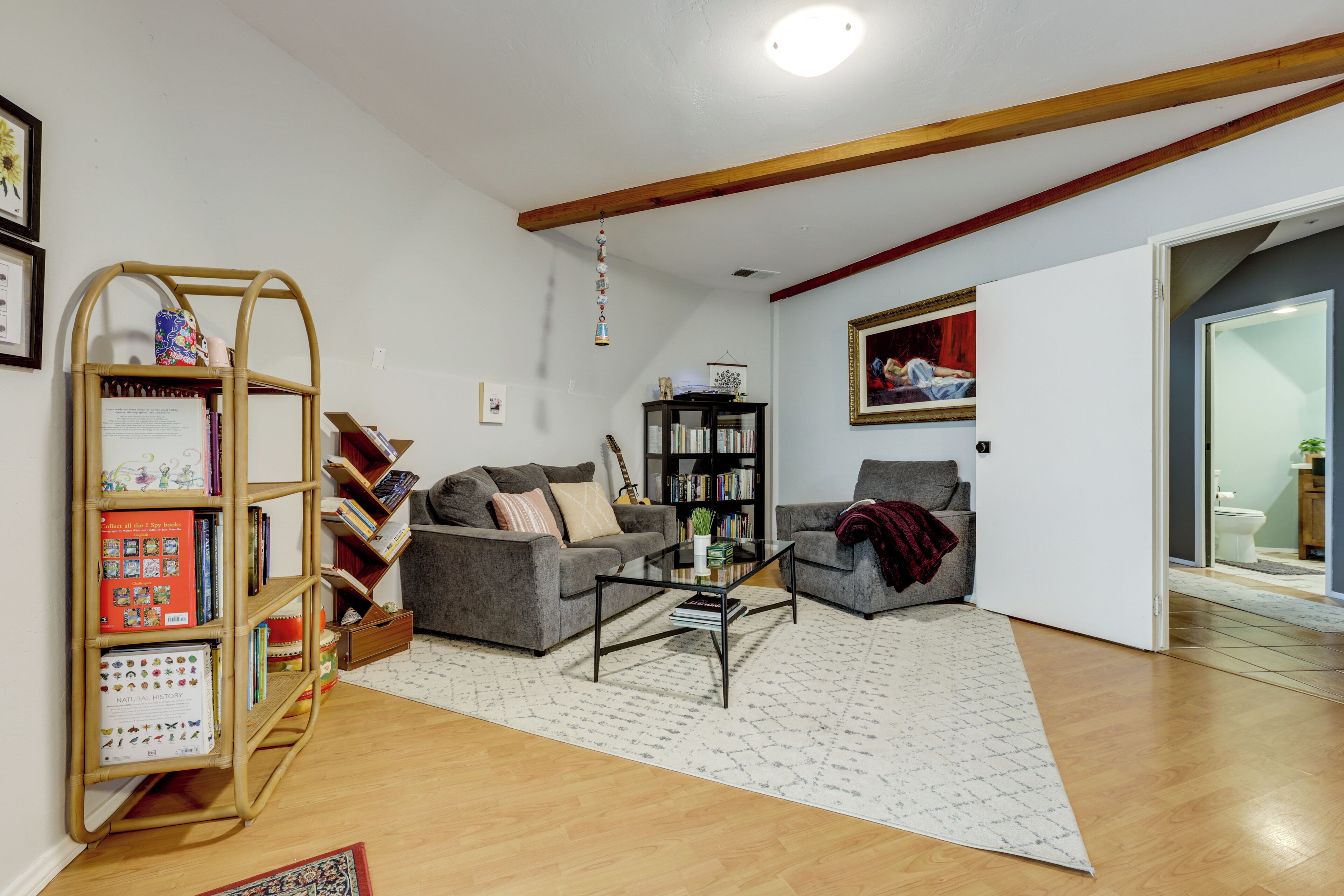A living room with a sofa, armchair, coffee table, bookshelf, and a hanging decoration.