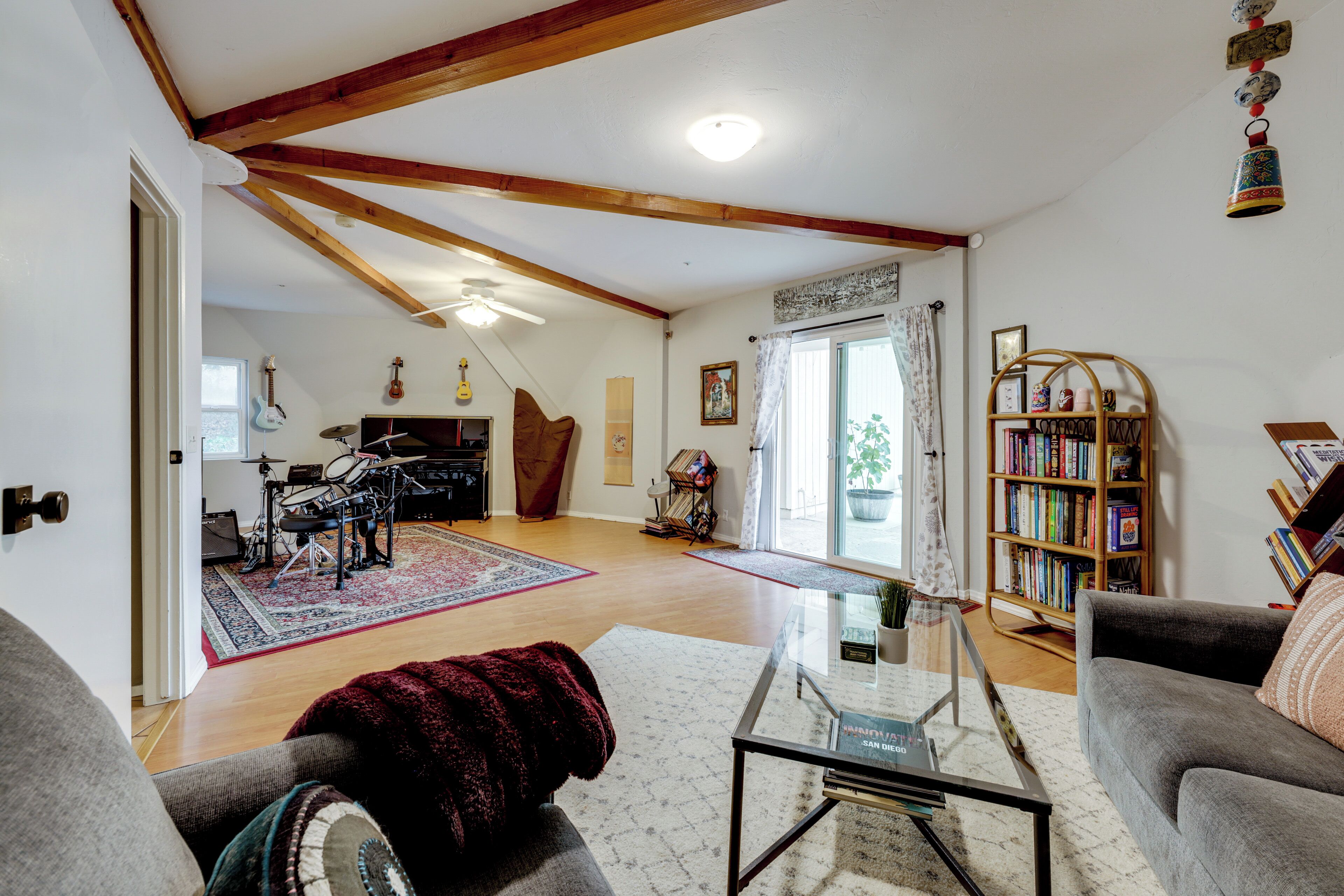 A spacious living room with a high ceiling, a piano, a bookshelf, and a cozy seating area.