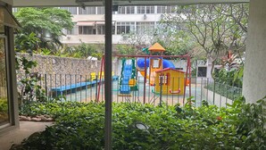A view of a playground with slides and climbing structures, surrounded by greenery and a stone wall. - Spacious 3-bedroom apartment in Copacabana, 3 blocks from the beach. (Rio de Janeiro)