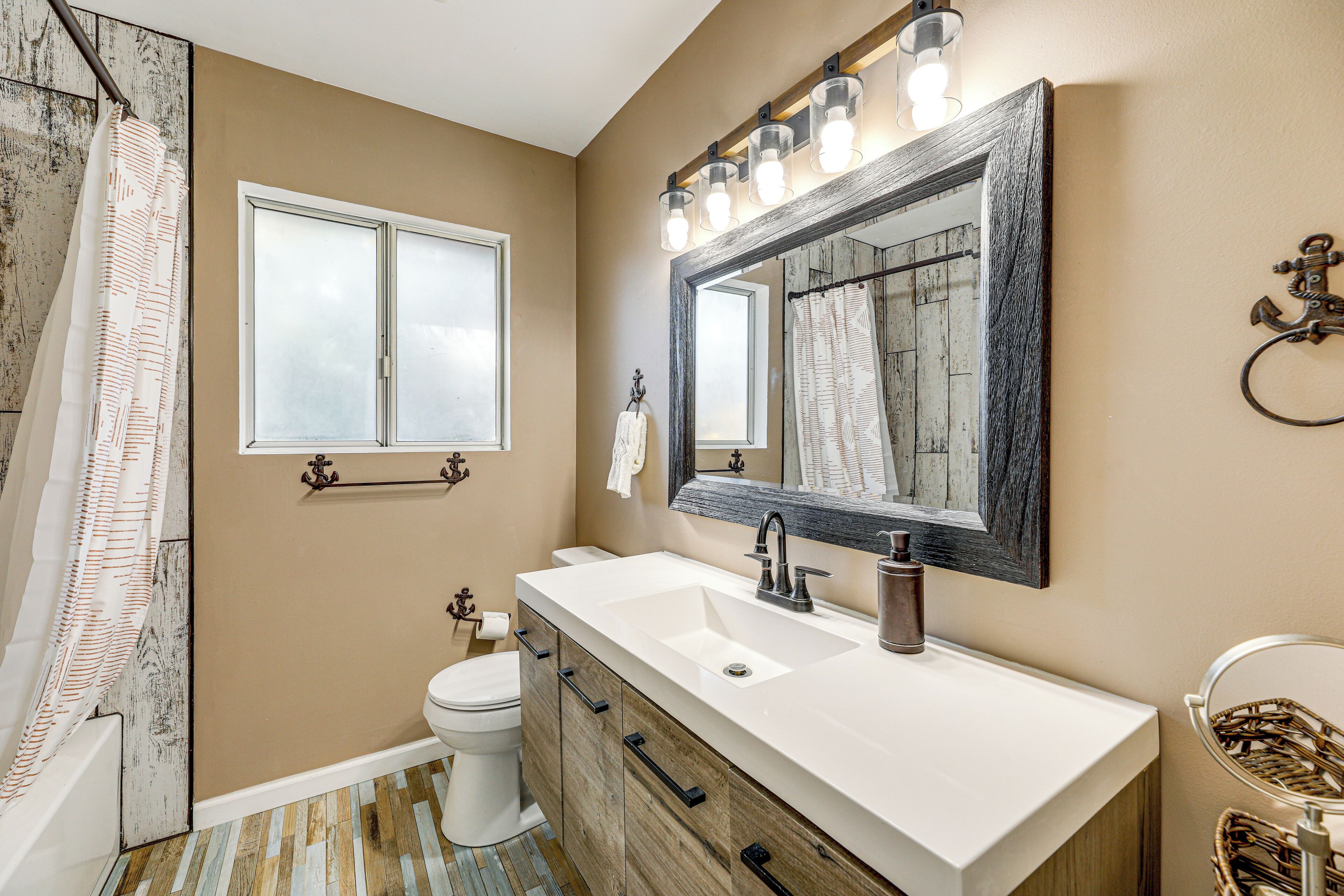 A bathroom with a large mirror, a white sink, and a wooden vanity.