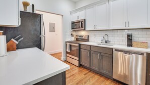 Una cocina moderna con armarios blancos, electrodomésticos de acero inoxidable y piso de madera.