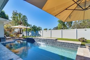 Piscina com bordas revestidas, rodeada por um espaço de terraço com cadeiras e guarda-sóis.