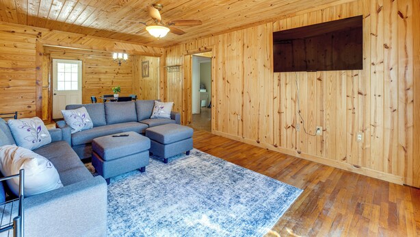 Una sala de estar acogedora con un sofá modular, un ventilador de techo y un televisor montado en la pared.