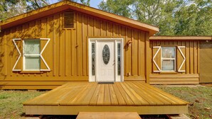 Una cabaña de madera con un porche delantero, una puerta con un tragaluz decorativo y una ventana pequeña con un diseño original.