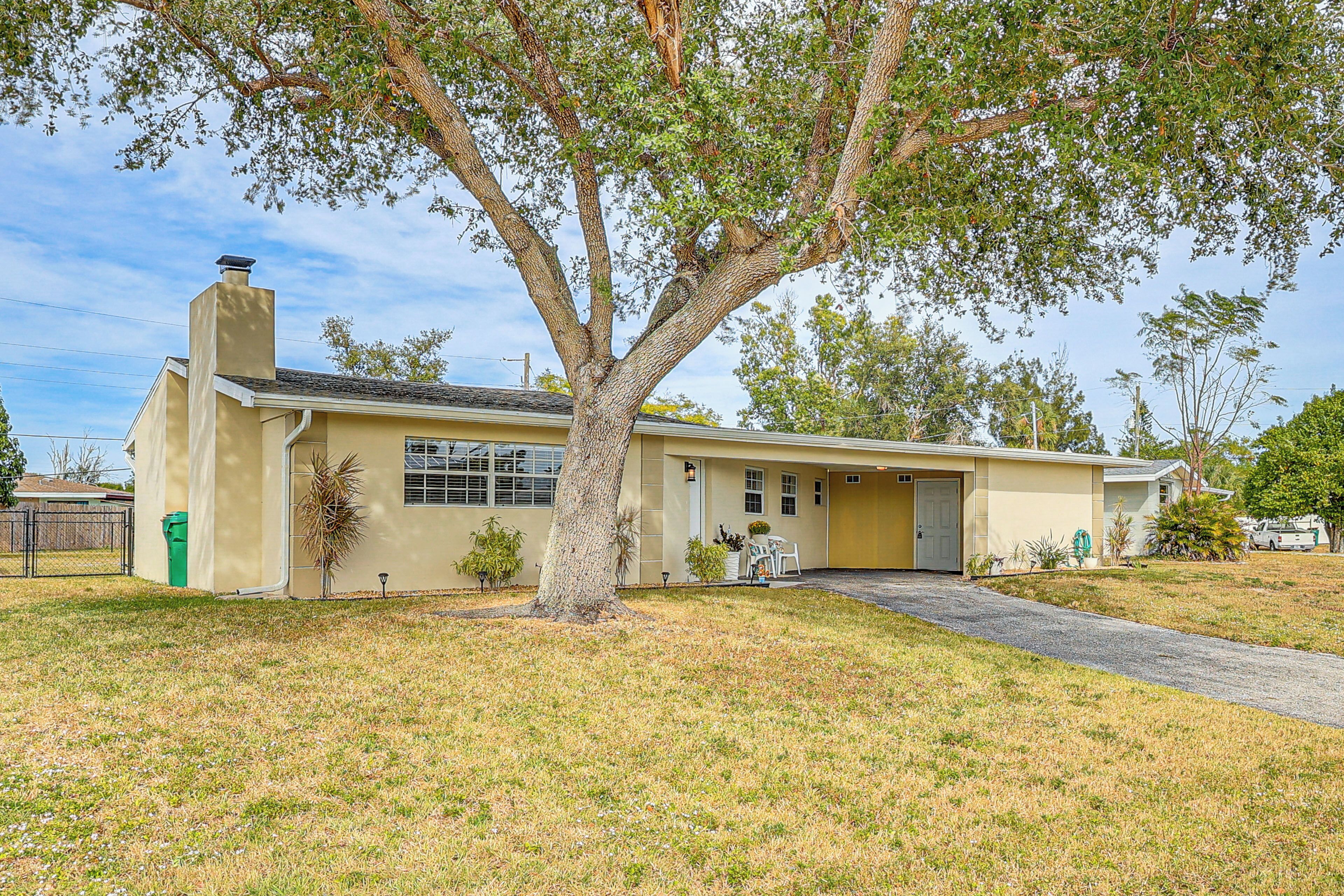 A single-story house with a large tree in front, a garage, and a small front yard.