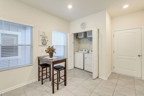A compact laundry room with a washing machine, dryer, and a small table with chairs. - 4 Mi to Everbank Stadium! Stylish Suburban Retreat (Jacksonville)