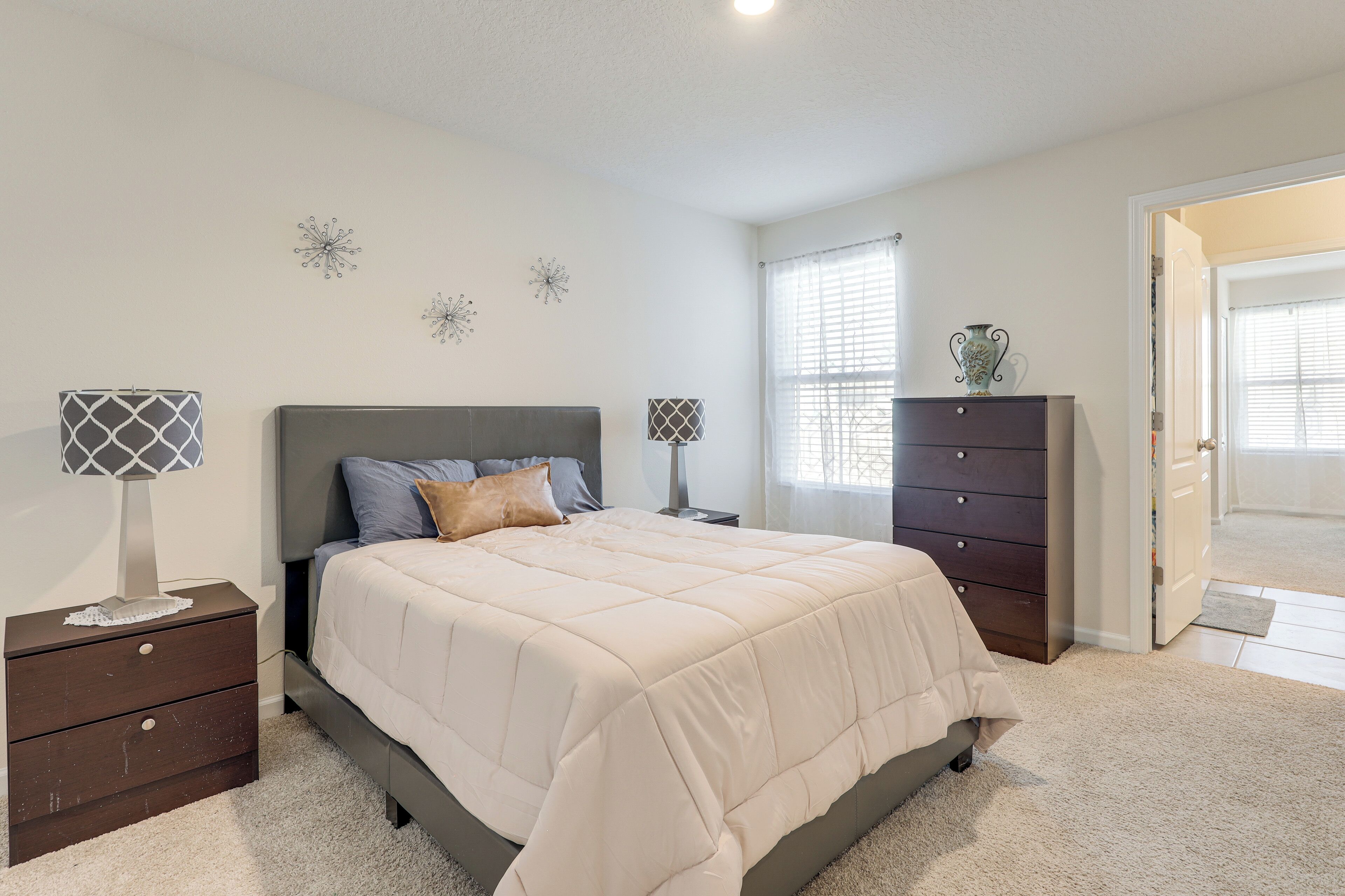 A bedroom with a bed, nightstands, a dresser, and decorative wall art.