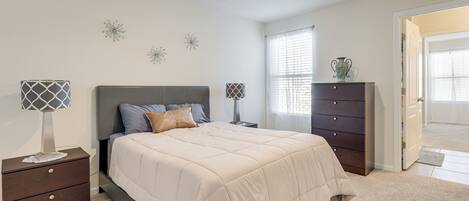 A bedroom with a bed, nightstands, a dresser, and decorative wall art.