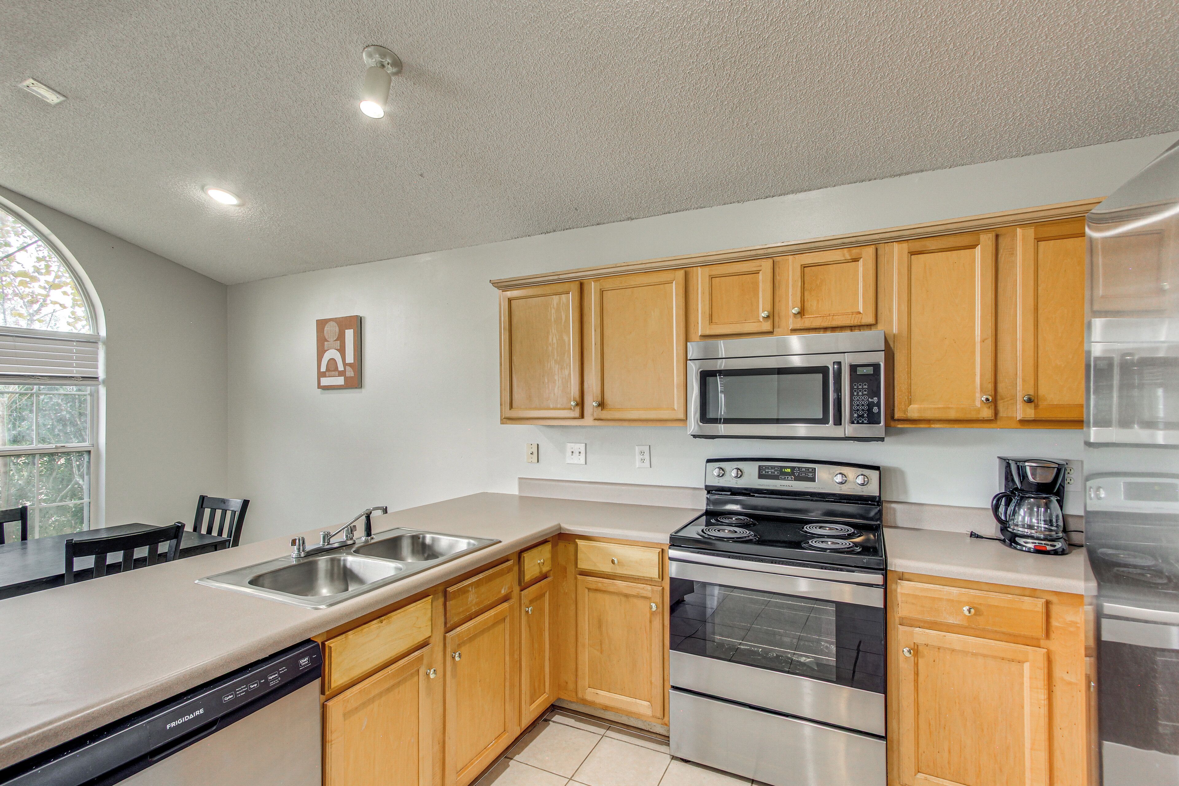 A kitchen with wooden cabinets, stainless steel appliances, a dishwasher, and a large window.