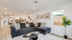 A modern living room with a sectional sofa, a coffee table, and a potted plant. - Updated Home w/ Hot Tub in Houston's Northside! (Houston)