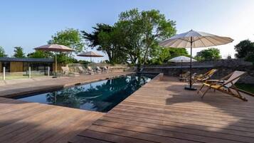 Alberca al aire libre, sombrillas en la alberca y camastros