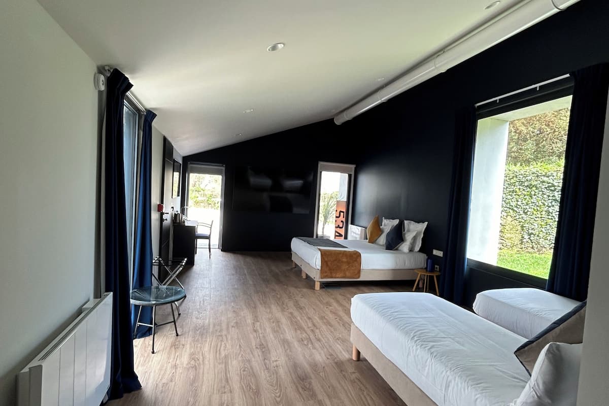Una habitación moderna y luminosa, con suelo de madera, un sofá, una cama y una zona de comedor con mesa y sillas.