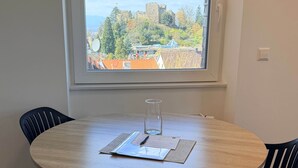 A round dining table with a clear view of a castle through a window. - Apartment No.07 with one bedroom (Badenweiler)