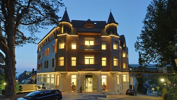 Un grand immeuble à plusieurs étages, doté d’une façade symétrique, de grandes fenêtres et d’une entrée centrale.