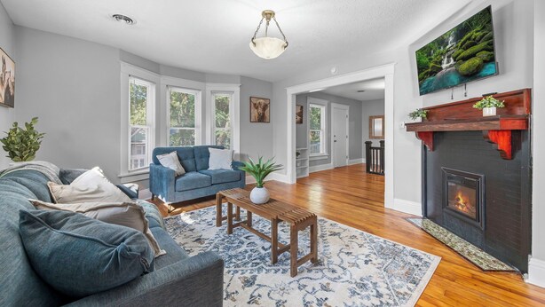 A spacious living room with a blue sofa, a wooden coffee table, and a fireplace. - The Maple Attic – Bright 3BR Retreat Near Downtown (Saint Joseph)