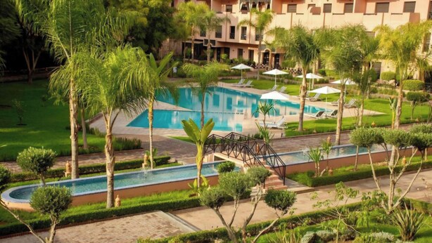 A resort with a swimming pool, palm trees, and a well-maintained garden. - Comfortable poolside apartment near the medina (Marrakesh)