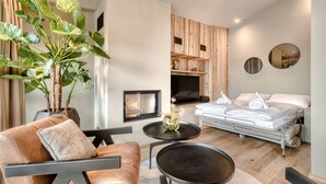 Un salon moderne comprenant un canapé, une table basse, une plante en pot, une cheminée et un lit avec des serviettes.