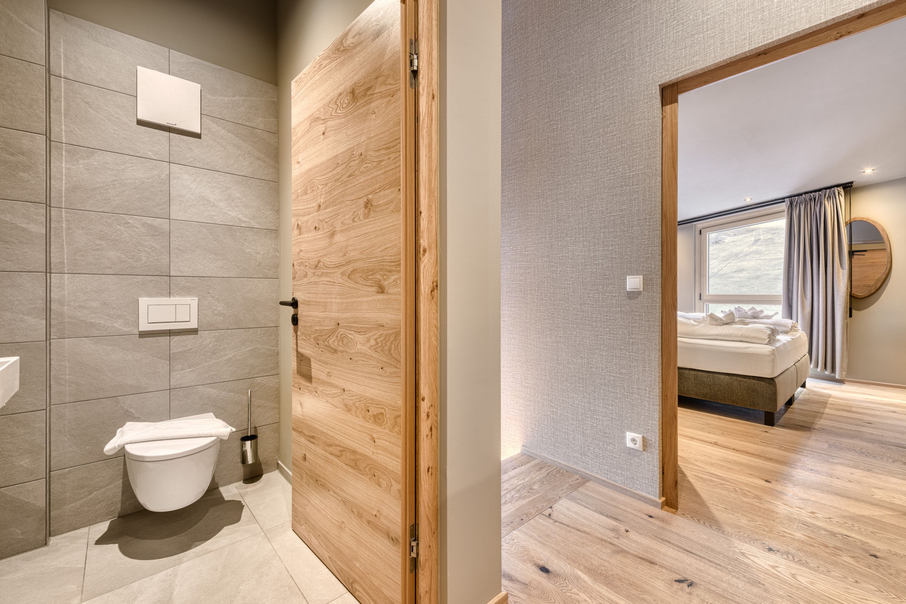 Een moderne badkamer met toilet, een houten deur en een douchecabine.