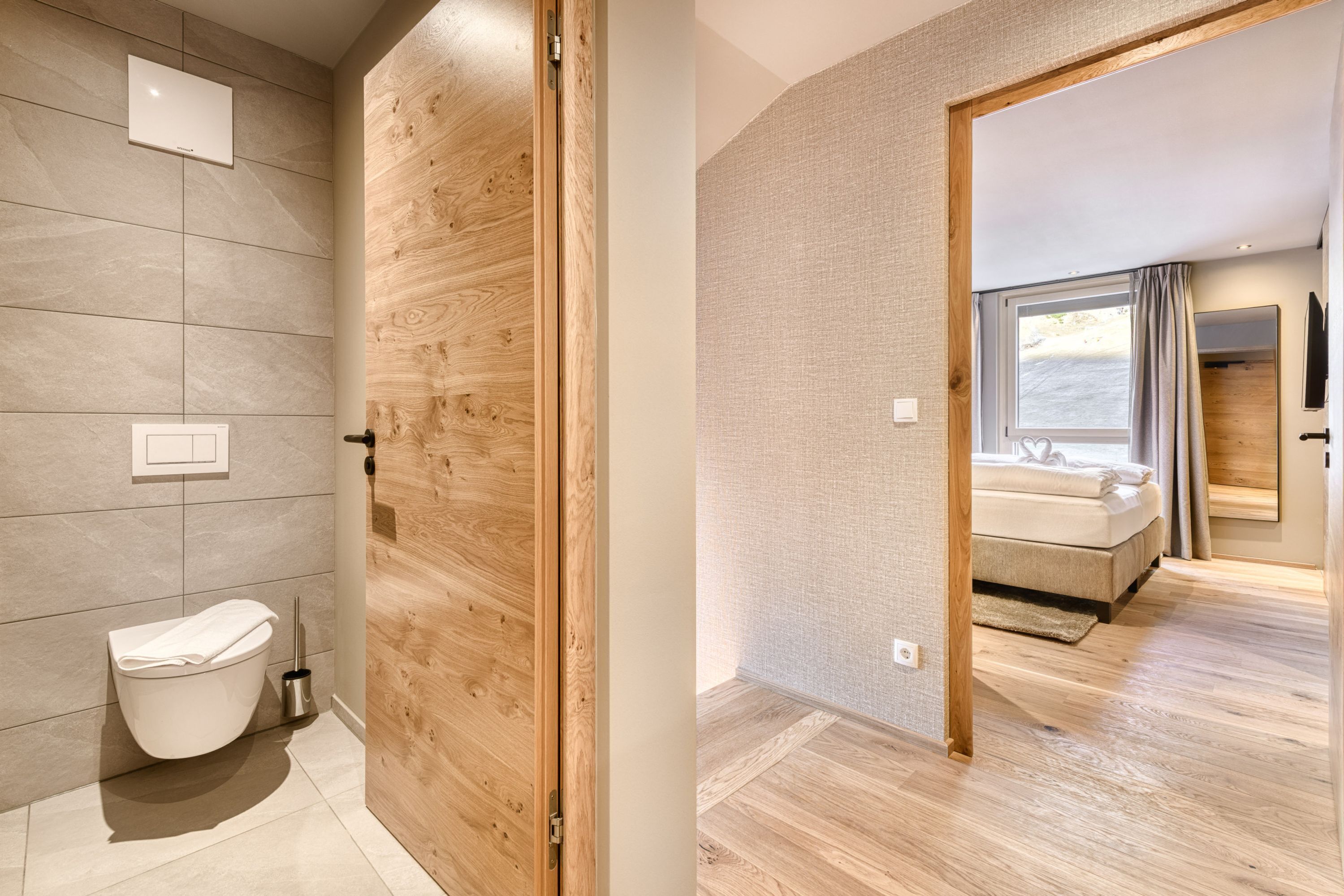 Un baño moderno con inodoro, puerta de madera y zona de ducha.
