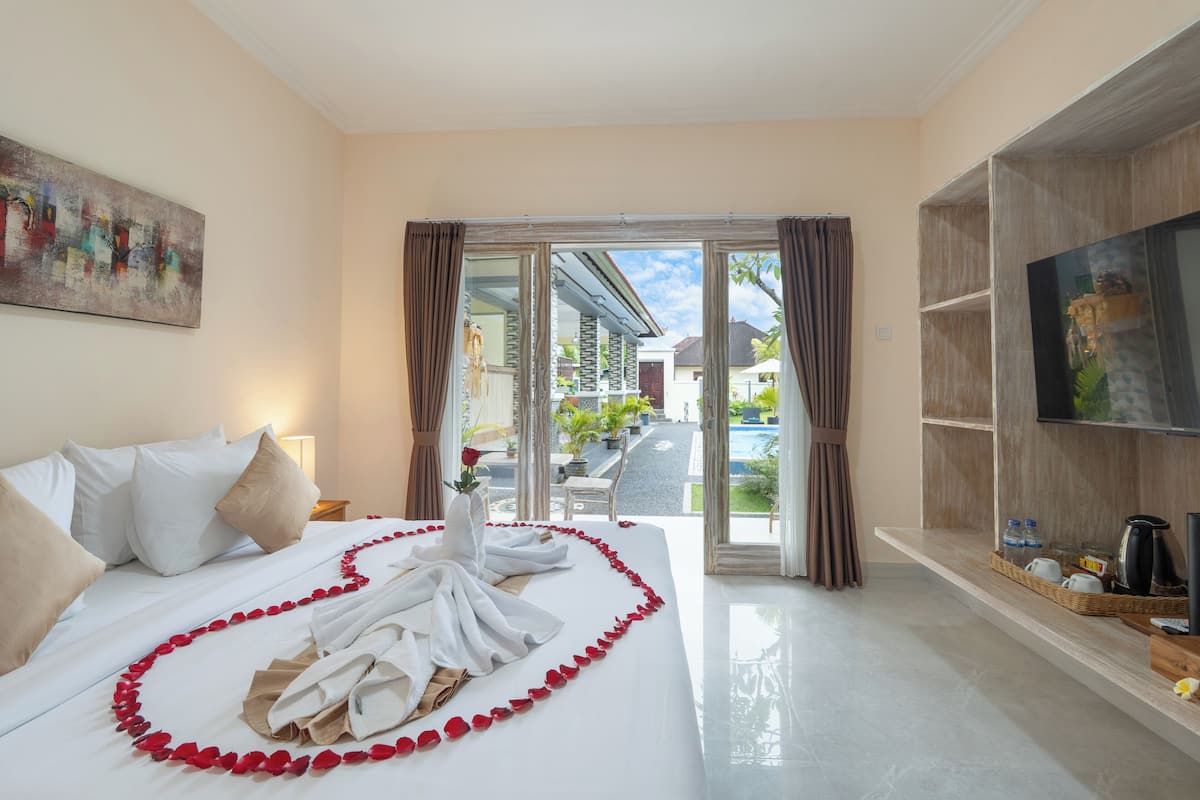 A hotel room with a bed, a TV, a balcony with a view of the outside, and a painting on the wall.