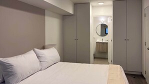 Un dormitorio con cama, lámpara de noche y armario.