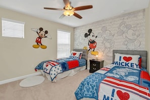 A bedroom with two beds, Mickey Mouse wall art, and a ceiling fan. - Spacious Family Home w Pool Hot Tub BBQ (Kissimmee)