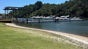 Un port de plaisance avec des bateaux amarrés, une zone herbeuse et un ciel bleu dégagé.