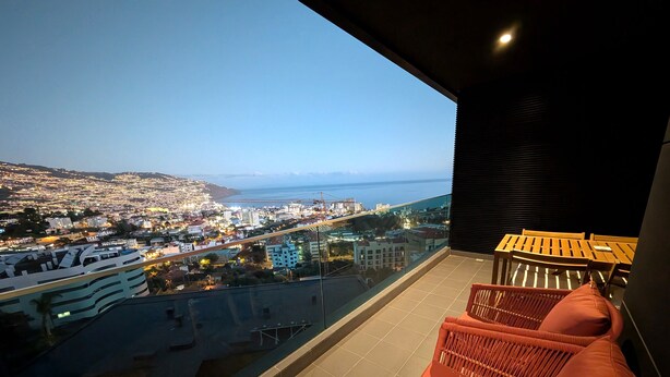 Ein Balkon mit Blick auf eine Stadtlandschaft und das Meer.