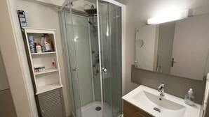 Une salle de bain moderne avec une douche à parois de verre, un lavabo blanc et un miroir au-dessus.