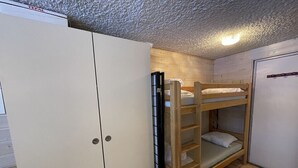 Une chambre avec un lit superposé, une armoire et une porte.