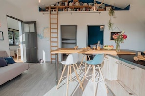 Une cuisine moderne dotée d’un îlot central en bois, de tabourets de bar et d’un espace en mezzanine avec des étagères.