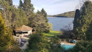 Una propiedad frente al lago con piscina, zona de barbacoa y una pequeña construcción.