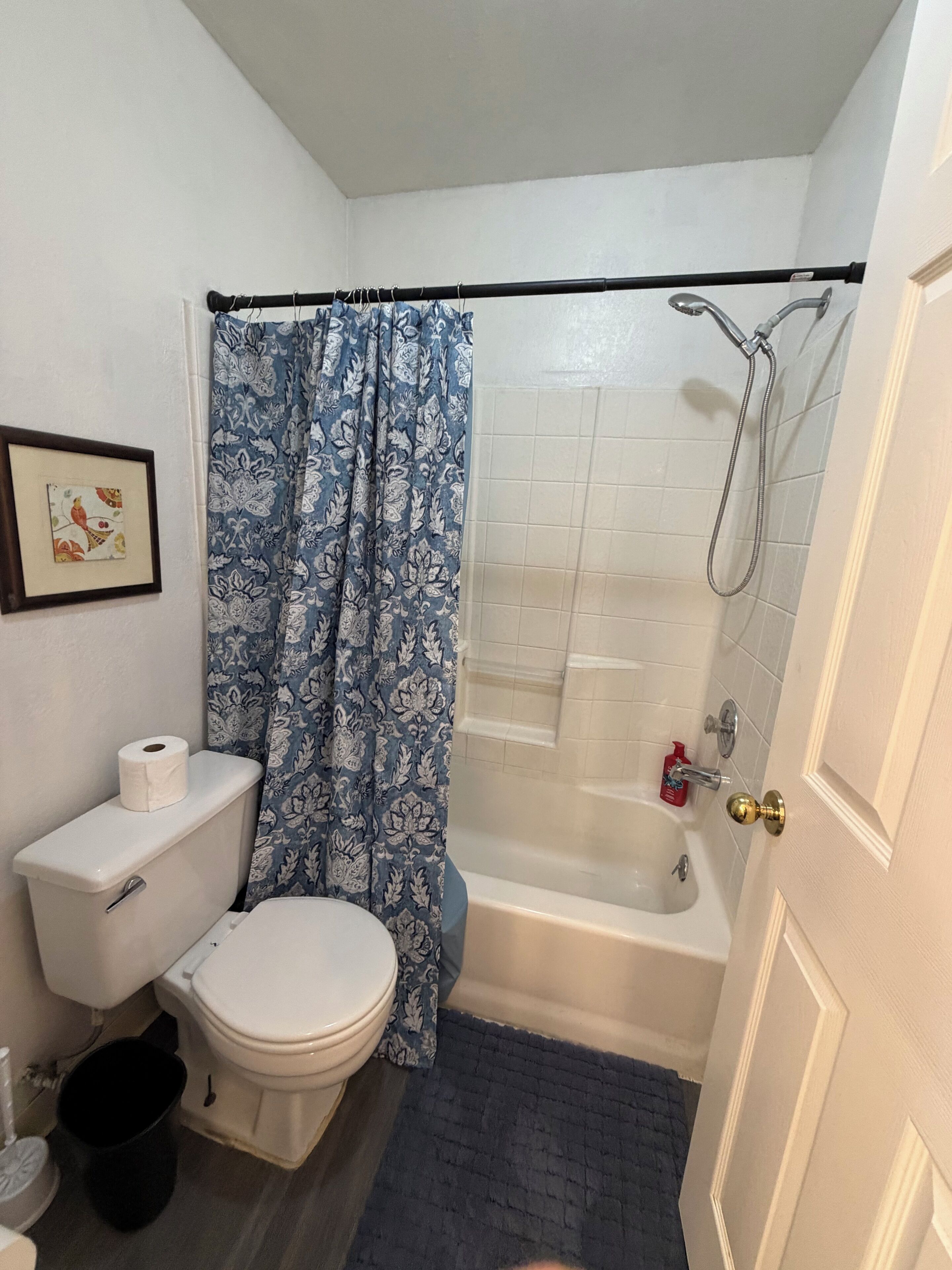 Un baño con inodoro, ducha y una cortina de baño azul estampada.
