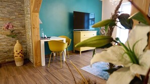 Ein Zimmer mit Holzboden, einem Schreibtisch mit Stuhl, einem Fernseher und einem gelben Schrank.